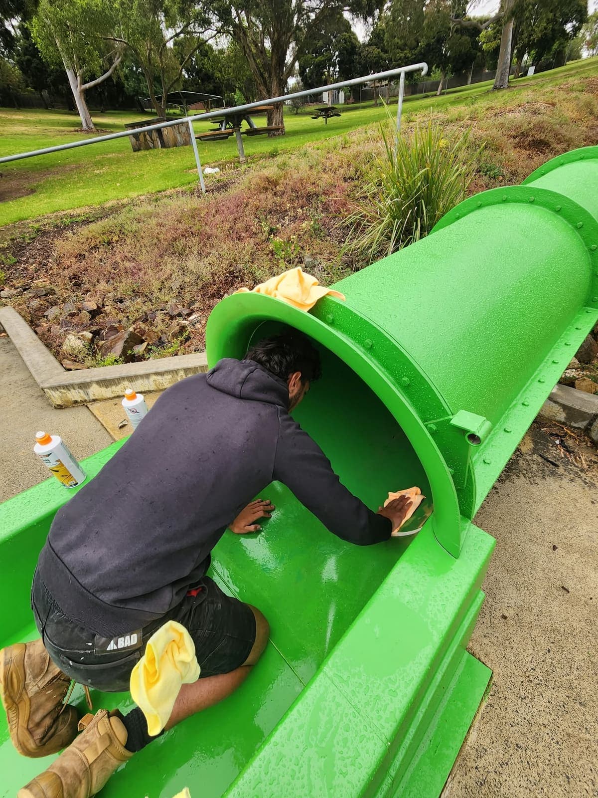 A REST technician kneeling in a freshly resurfaced green flume, hand finishing the inside of the tube